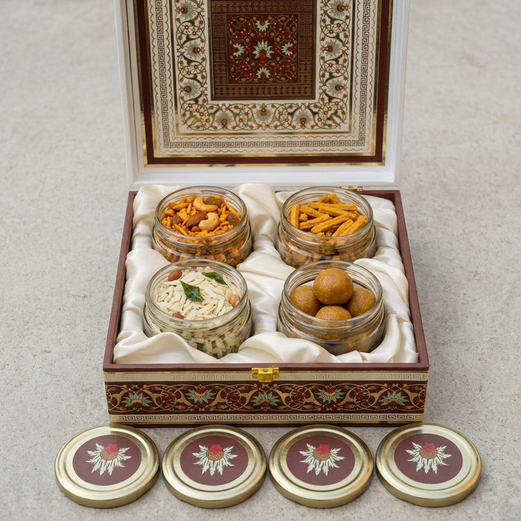 Open snack gift hamper with uncovered jars of chakli sticks, white chivda, masala chivda and besan ladoo